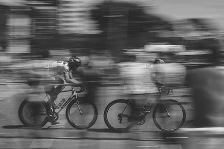 two person racing a bicycle grayscale photo