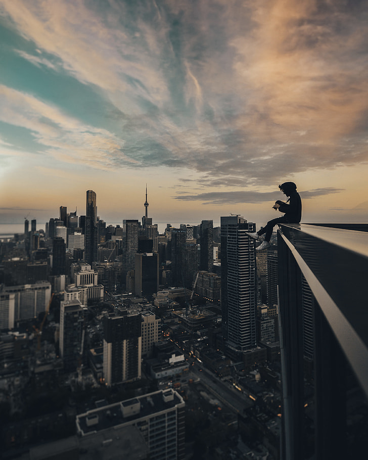person sitting on the top of building photography during daytime