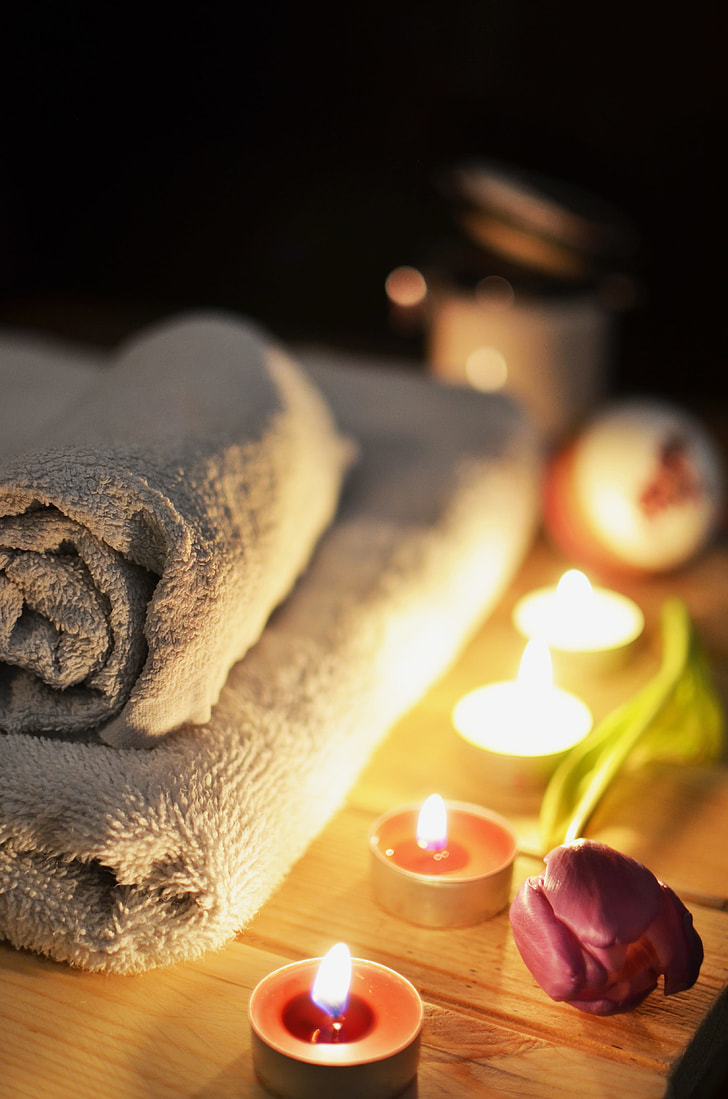 massage table with towel beside candle tealight