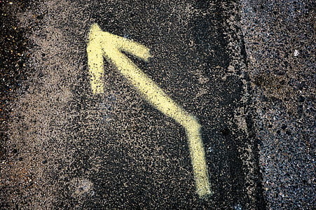 Yellow Left Arrow Sign on Black and Grey Surface