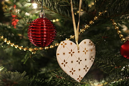 red bauble and white heart ornament hanged on green Christmas tree