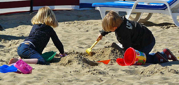 two children crawling on sand