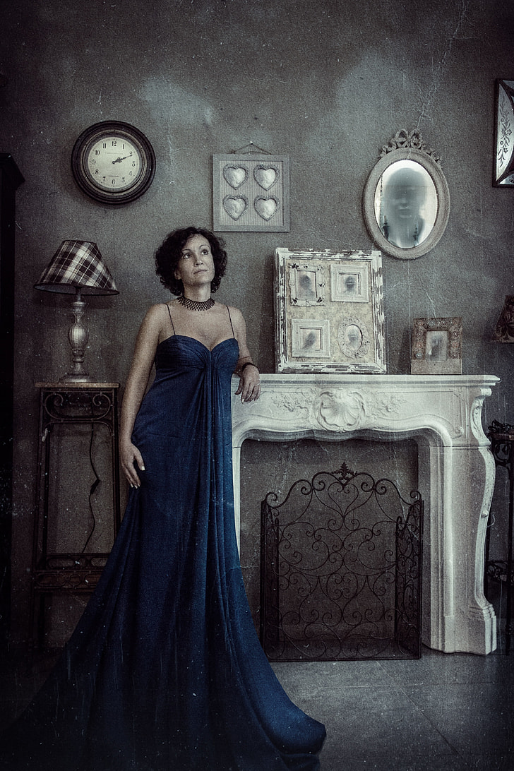 women's blue spaghetti strap dress stand near white fireplace surround