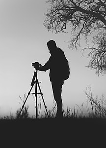 silhouette of man holds tripod camera at daytime