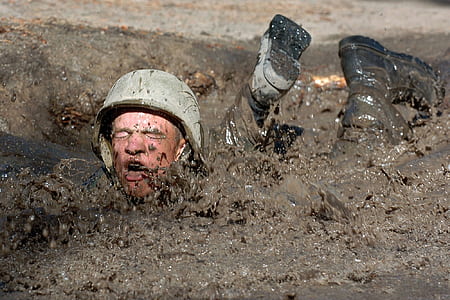 soldier lying prone in mud during daytime