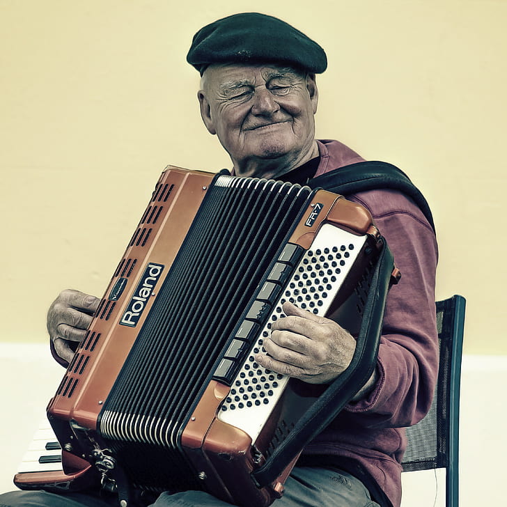 man wearing flat hat and playing accordion