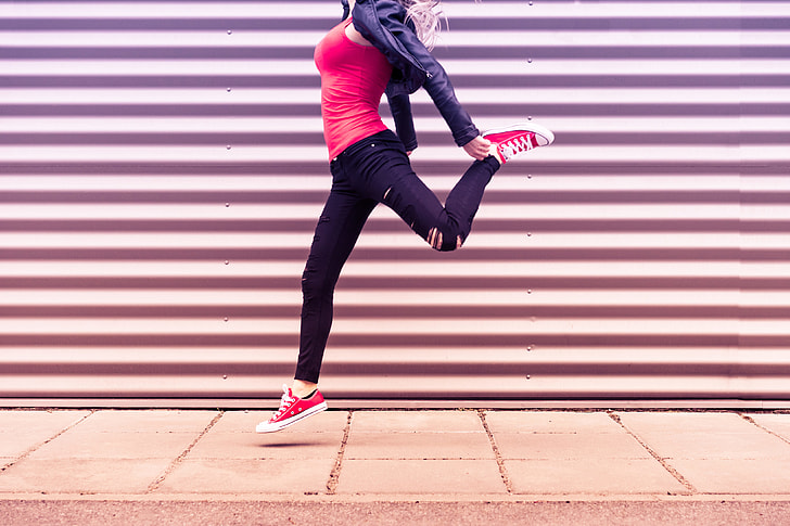 Young Happy Woman Jumping in Front of Metal Wall