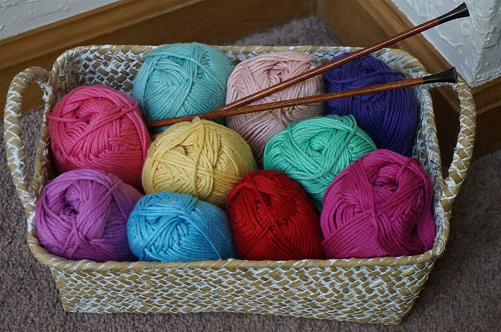 assorted-color yarn rolls in basket with hooks