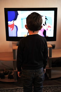 kid in black crew-neck sweater standing in front of black flat screen television