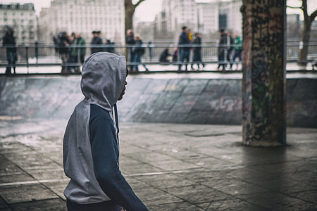 A young man wearing a hooded top stands on the Southbank in London, England
