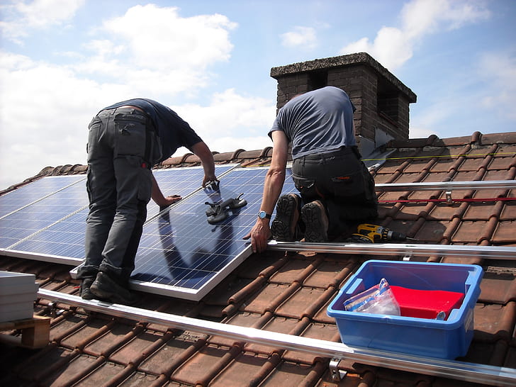 two man putting solar panels on roof