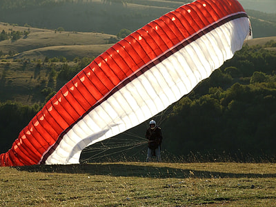 man in black suit with red parachute