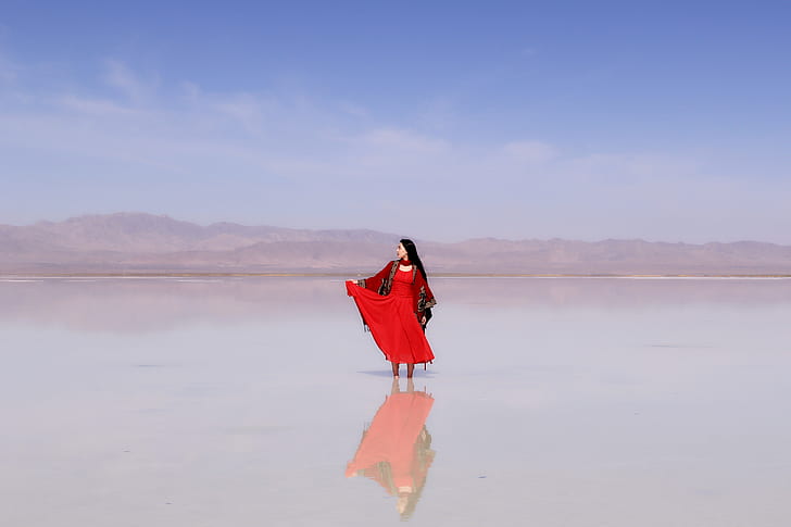 woman in red sari dress on body of water during daytime