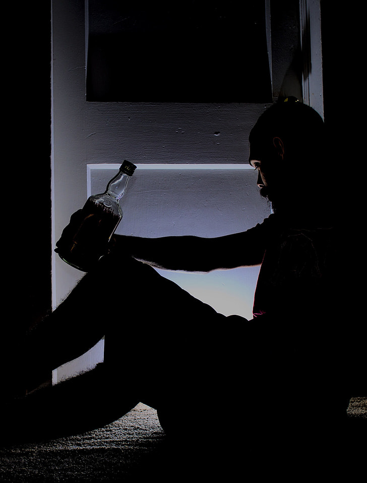 man holding bottle sitting on floor