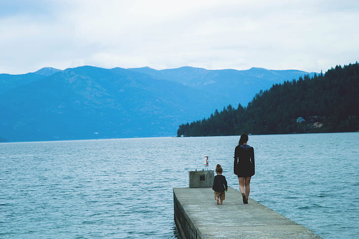 woman and child walking on the dock during daytime