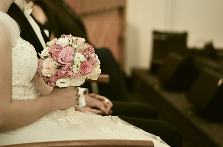 selective focus photography of woman in wedding dress holding bouquet of flowers