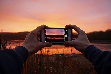 Man capturing a stunning sunset with his mobile iPhone smartphone camera