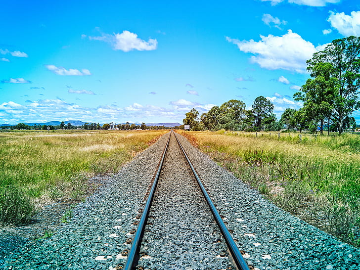 railroad track near green grass field