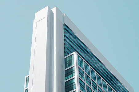 low-angle photography of white concrete framed curtain-wall high-rise building under blue sky