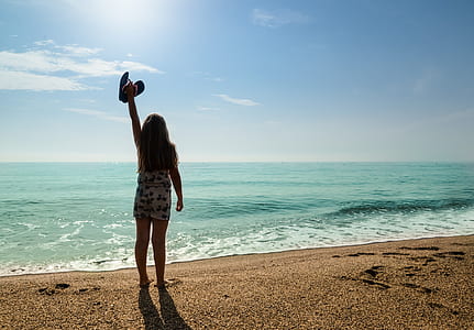 woman raising hand in front of ocean