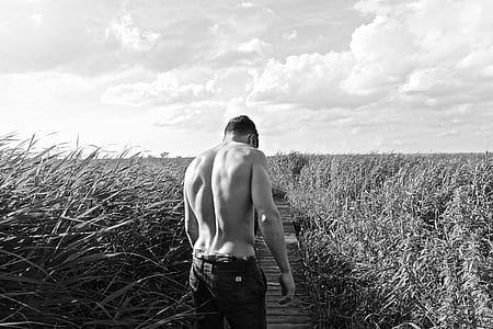 grayscale photography of man in the middle of the grass field