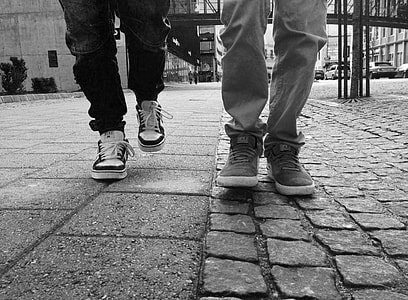 grayscale photo of two persons wearing sneakers