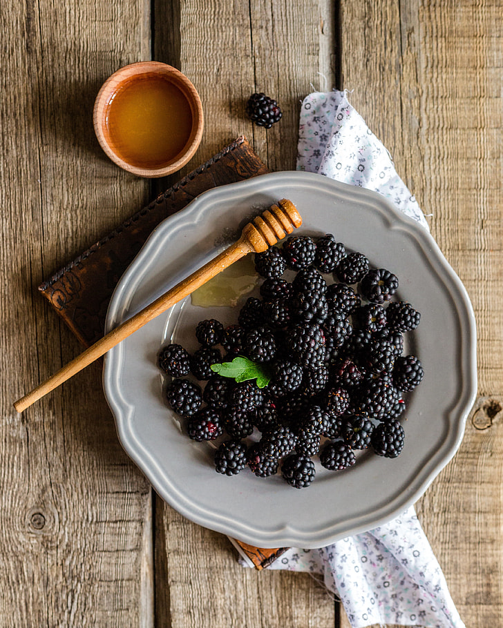 black berries on white ceramic plate on brown table top