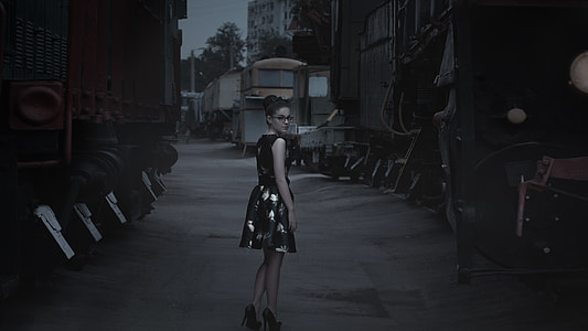 woman in dress walking near trains