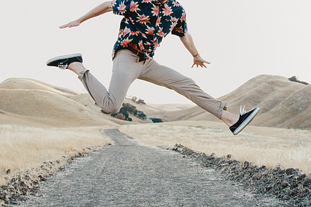 jump shot of person wearing blue, red, yellow button-up short-sleeved shirt and gray pants during day time