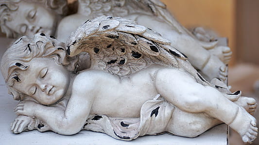 selective focus photography of sleeping cherub figurine