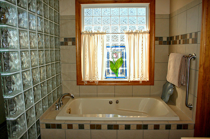 rectangular white enamel bathtub inside room with gray wall tiles