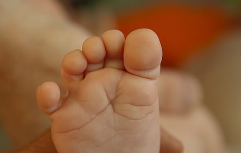 toddler's foot on selective focus photography