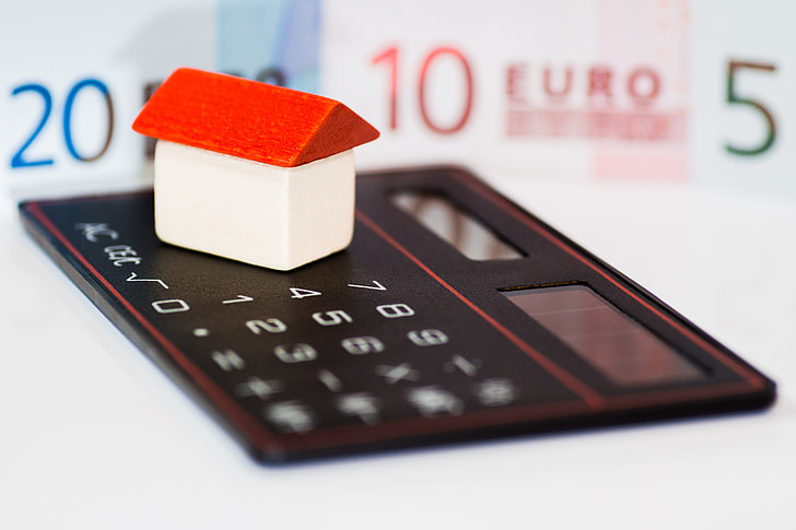 white and red house miniature on top of desk calculator