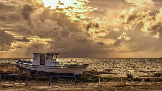 brown and white boat on sandy shore during sunset