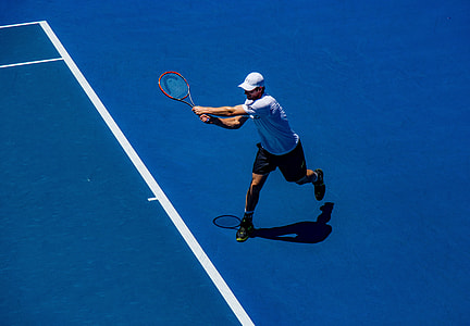 man in white shirt and black shorts playing tennis
