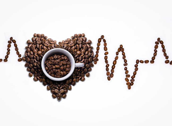 coffee beans formed in shape of heart beat with white ceramic mug