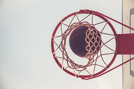 brown Spalding basketball on red basketbal ring
