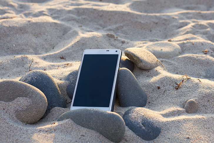 smartphone on black stone and sand
