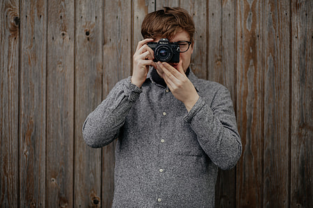 man in  gray coat jacket a holding an DSLR camera