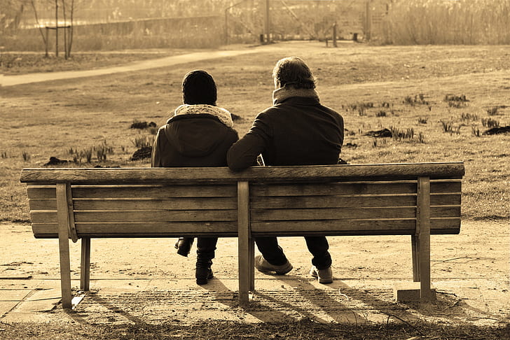 two person sitting on wooden bench
