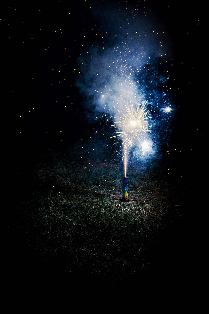photo of lighted firecracker on ground during night time