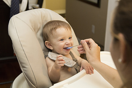 baby sitting on white high chair