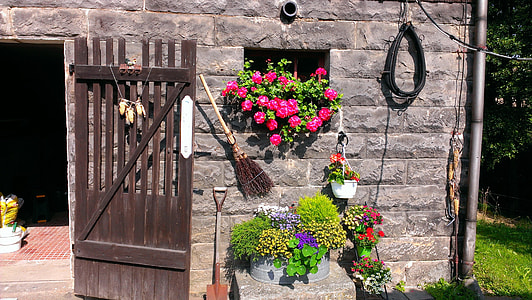 gray brick wall with flowers and wooden gate