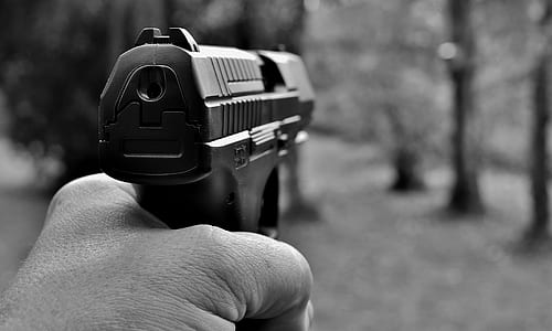 grayscale photography of a person holding black semi-automatic pistol