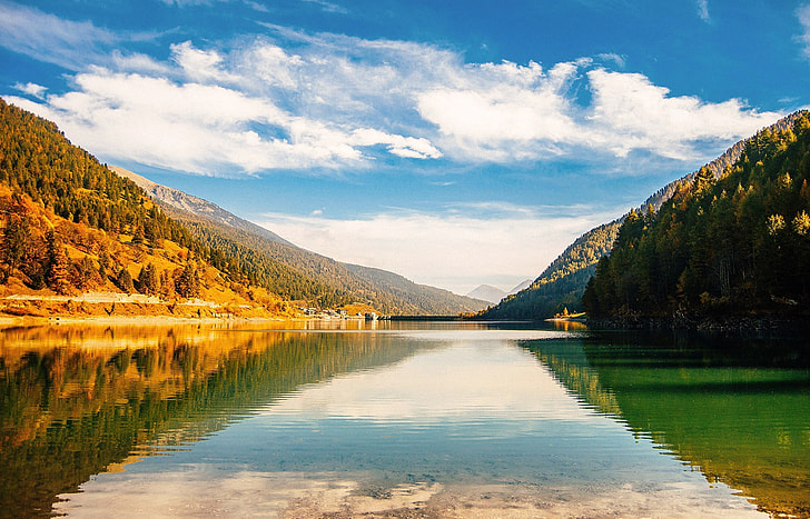 body of water beside mountain with trees during daytime