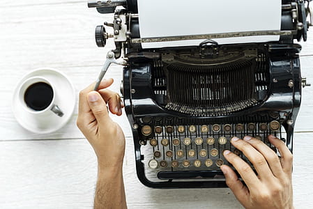 person using typewriter with coffee on the side