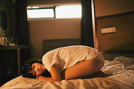 woman in white shirt kneeling on mattress