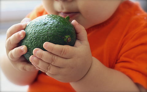 baby holding green fruit