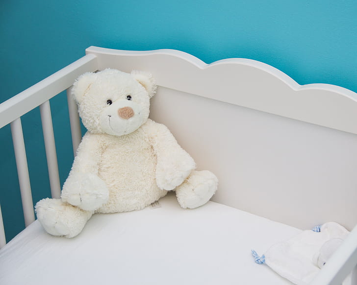 white bear plush toy on white wooden crib
