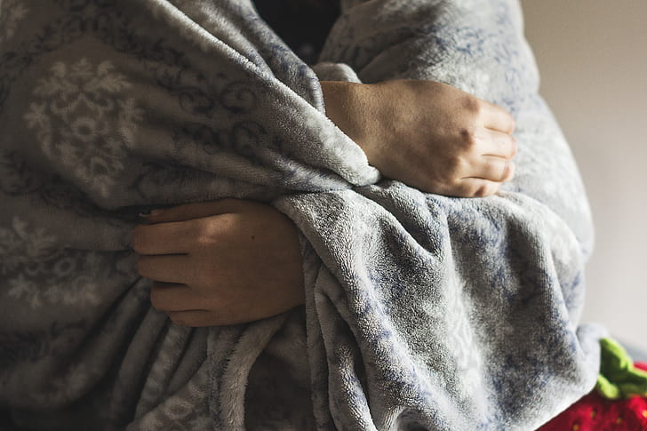 person wrapped in gray fleece blanket